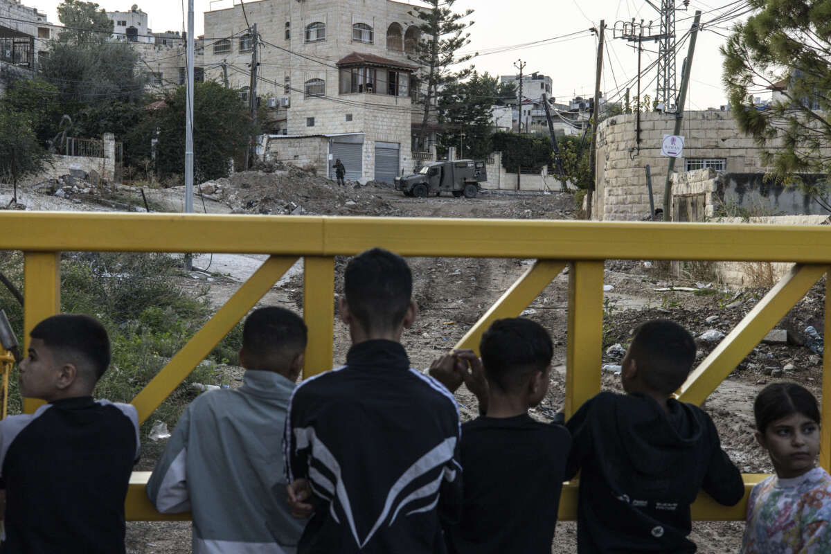 Palestinians wait behind a barrier to retreive their belongings during an Israeli army raid on the outskirts of the Jenin refugee camp in the occupied West Bank on November 27, 2025.