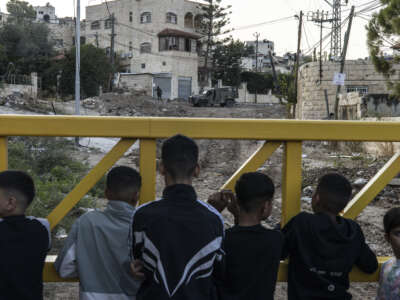 Palestinians wait behind a barrier to retreive their belongings during an Israeli army raid on the outskirts of the Jenin refugee camp in the occupied West Bank on November 27, 2025.