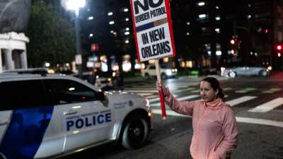 A woman holds a sign during a protest against the U.S. Border Patrol and Immigration and Customs Enforcement (ICE) outside of Hale Boggs Federal Building in New Orleans, Louisiana, on December 6, 2025.