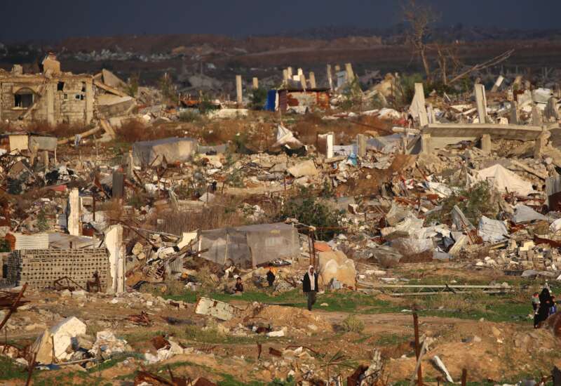 A man walks past homes and buildings destroyed by the Israeli military in the Nuseirat refugee camp in the central Gaza Strip, on December 13, 2025. Heavy rain has flooded tents and temporary shelters across Gaza, compounding the suffering of the territory's residents, nearly all of whom were displaced during more than two years of war.