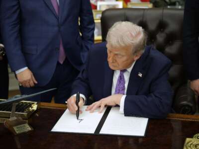 Donald Trump signs an executive order in the Oval Office of the White House on December 11, 2025, in Washington, D.C. The executive order curbs states' ability to regulate artificial intelligence, something for which the tech industry has been lobbying.