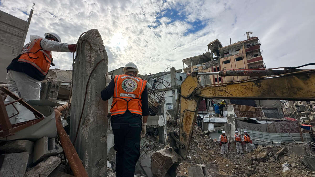 Civil defense workers and residents watch as an excavator clears rubble during a search operation in the Al-Amal neighborhood of Khan Yunis, Gaza Strip, on December 20, 2025. Civil defense teams are conducting search operations for the bodies of the Abu Hilal family in the Al-Amal neighborhood, months after they were killed on August 13, 2025.