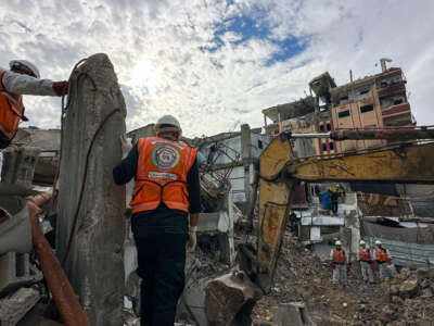 Civil defense workers and residents watch as an excavator clears rubble during a search operation in the Al-Amal neighborhood of Khan Yunis, Gaza Strip, on December 20, 2025. Civil defense teams are conducting search operations for the bodies of the Abu Hilal family in the Al-Amal neighborhood, months after they were killed on August 13, 2025.