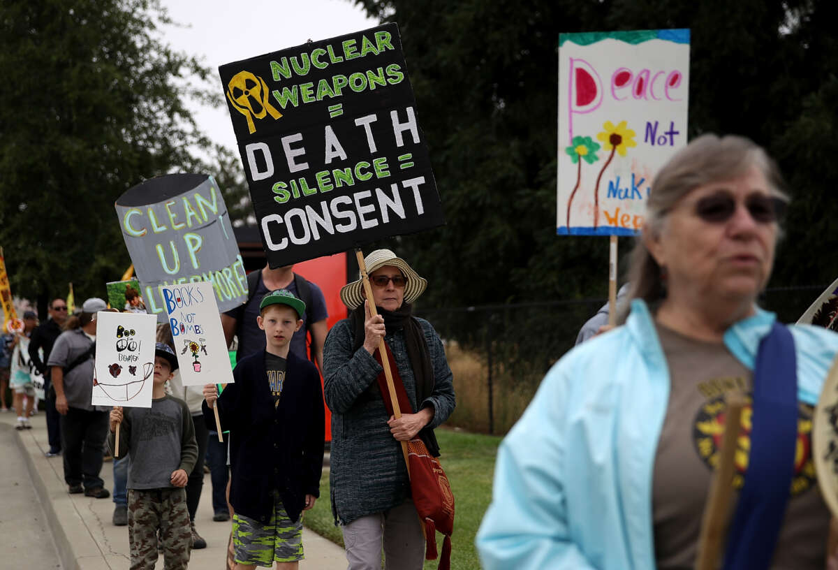Protester holds sign saying "Nuclear weapons = death. Silence = consent."