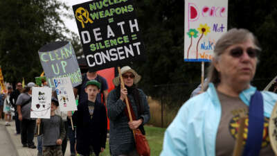 Protester holds sign saying "Nuclear weapons = death. Silence = consent."