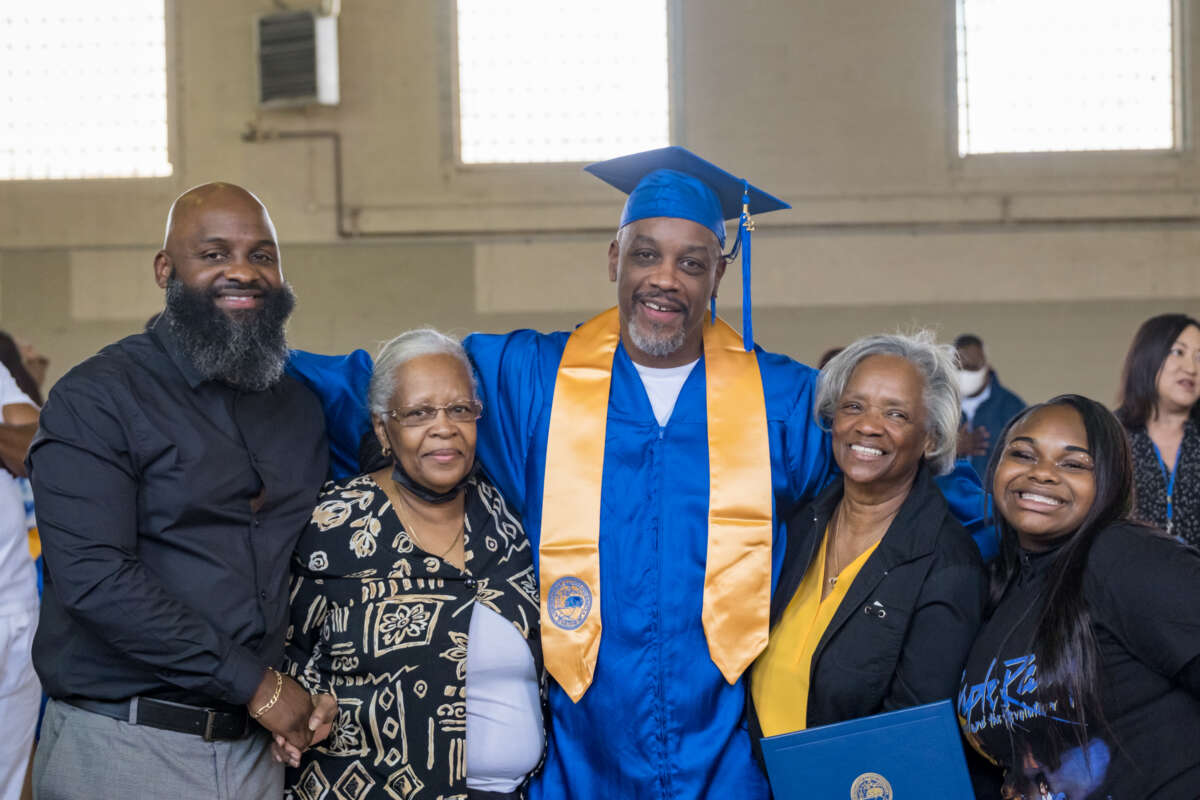 Michael Bell and his family stand together at the 2022 graduation ceremony for Northeastern Illinois University in partnership with Prison+Neighborhood Arts/Education Project (PNAP) at Stateville Correctional Center.
