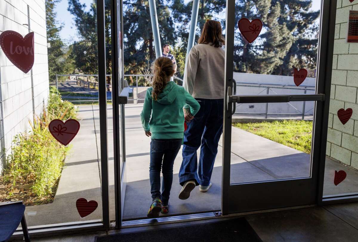 A parent holds her daughter's hand as they leave Project Camp, free child care to families impacted by the fires, at Eagle Rock Recreation Center on January 15, 2025 in Los Angeles, California,