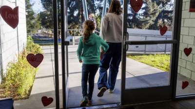 A parent holds her daughter's hand as they leave Project Camp, free child care to families impacted by the fires, at Eagle Rock Recreation Center on January 15, 2025 in Los Angeles, California,