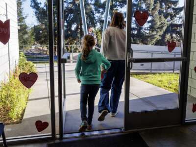 A parent holds her daughter's hand as they leave Project Camp, free child care to families impacted by the fires, at Eagle Rock Recreation Center on January 15, 2025 in Los Angeles, California,