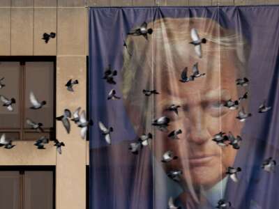 Birds fly past a giant banner with the image of President Donald Trump hanging on the outside of the U.S. Department of Labor on January 5, 2026 in Washington, D.C.