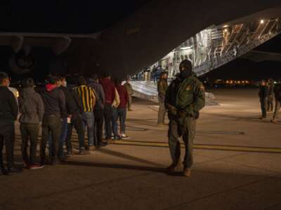 U.S. Customs and Border Protection Agents watch immigrants board a deportation flight at the Tucson International Airport, in Tucson, Arizona, on January 23, 2025.
