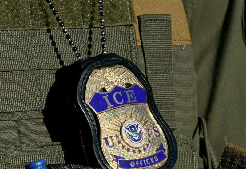 A badge hangs over the uniform of an Immigration and Customs Enforcement (ICE) agent.