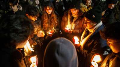 Vigil-goers hold candles and sing together in Lippitt Memorial Park in Providence, Rhode Island, on December 14, 2025, following a mass shooting at Brown University that left two dead and nine injured.