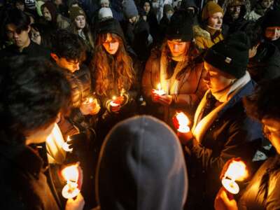 Vigil-goers hold candles and sing together in Lippitt Memorial Park in Providence, Rhode Island, on December 14, 2025, following a mass shooting at Brown University that left two dead and nine injured.