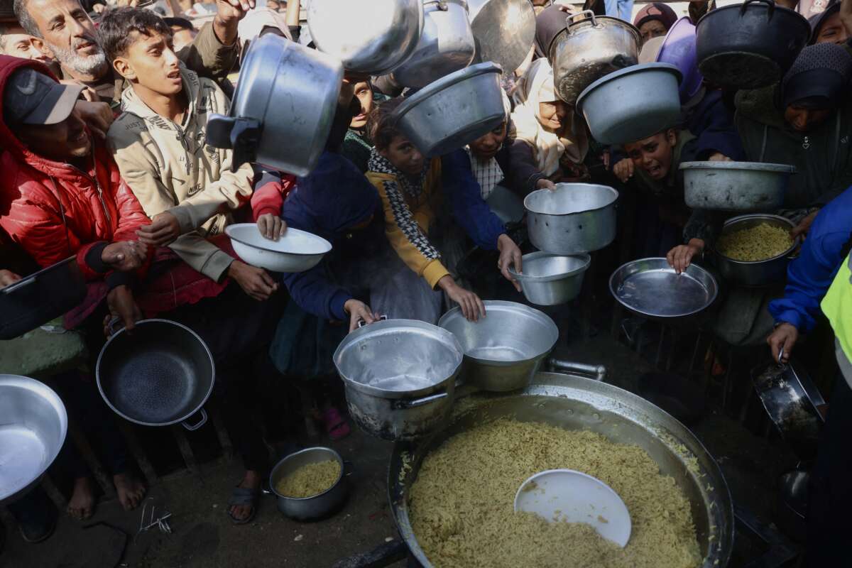 Displaced Palestinians gather to receive donated food portions at a charity kitchen in Khan Yunis in the southern Gaza Strip on December 17, 2025.