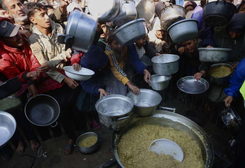 Displaced Palestinians gather to receive donated food portions at a charity kitchen in Khan Yunis in the southern Gaza Strip on December 17, 2025.