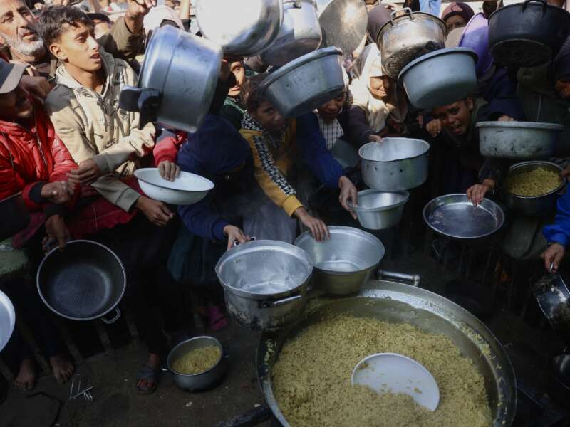 Displaced Palestinians gather to receive donated food portions at a charity kitchen in Khan Yunis in the southern Gaza Strip on December 17, 2025.