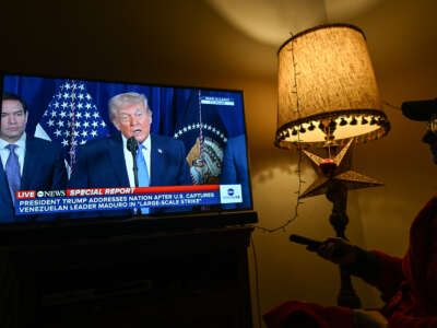 A woman watches ABC News Live as U.S. President Donald Trump addresses the nation following a U.S. special military operation in Venezuela that led to the capture of Venezuelan President Nicolás Maduro on January 3, 2026.