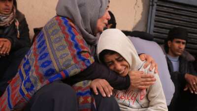 Palestinians mourn after three members of the Al-Rjodi family were killed in an Israeli strike in Deir al-Balah in the central Gaza Strip on January 21, 2026.