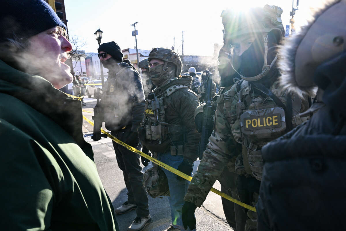 A man speaks to federal agents as demonstrators gather near the site where a man was shot by federal agents earlier in the morning in Minneapolis, Minnesota, on January 24, 2026.