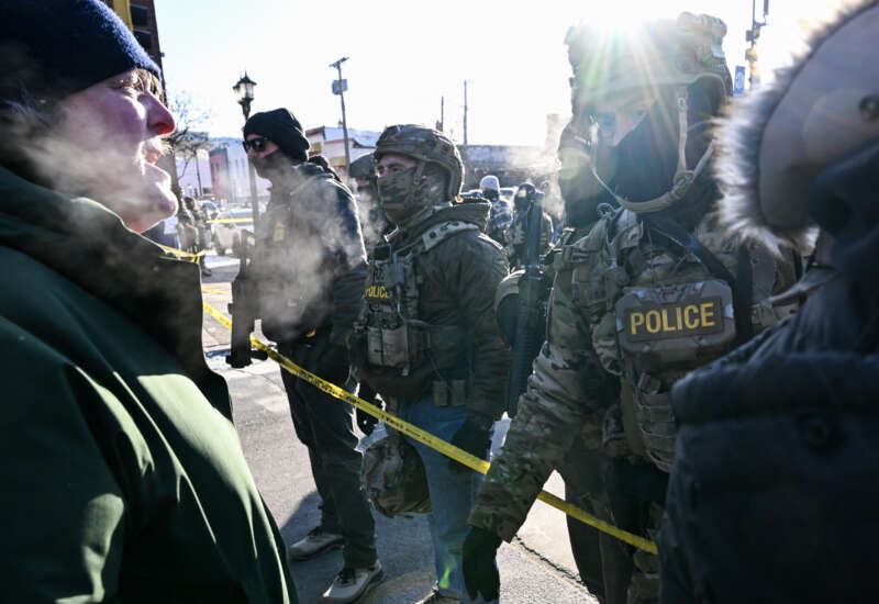 A man speaks to federal agents as demonstrators gather near the site where a man was shot by federal agents earlier in the morning in Minneapolis, Minnesota, on January 24, 2026.