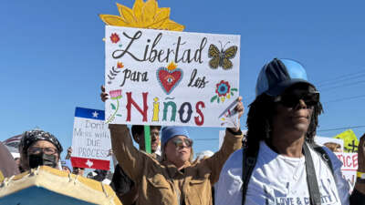 A protester holds a sign calling for freedom for children during a demonstration and vigil outside the South Texas Family Residential Center in Dilley, Texas, on January 28, 2026.