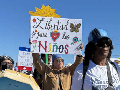 A protester holds a sign calling for freedom for children during a demonstration and vigil outside the South Texas Family Residential Center in Dilley, Texas, on January 28, 2026.