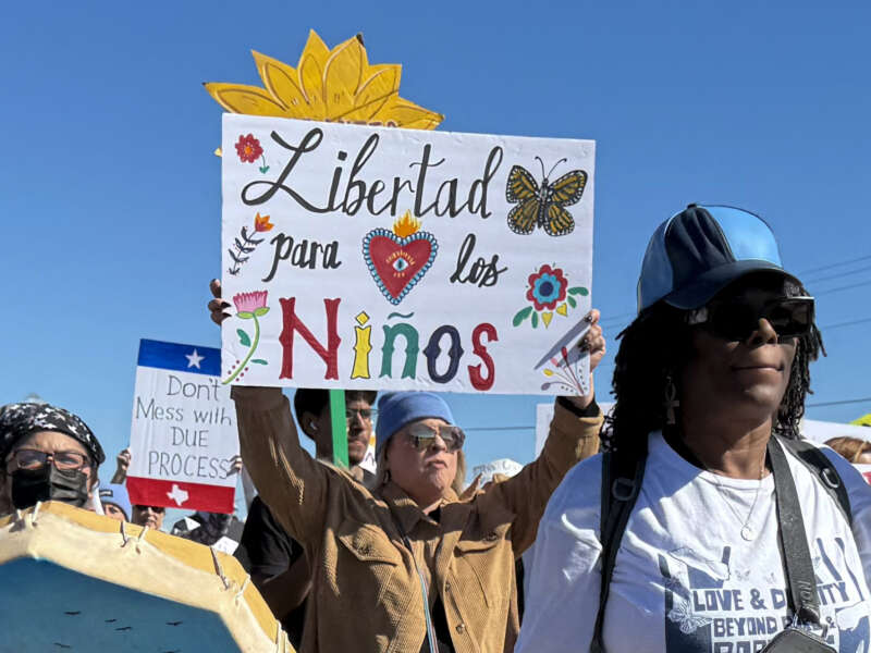 A protester holds a sign calling for freedom for children during a demonstration and vigil outside the South Texas Family Residential Center in Dilley, Texas, on January 28, 2026.