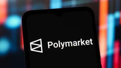 The Polymarket logo is seen displayed on a smartphone screen.