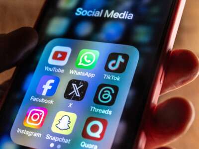 In this photo illustration, an iPhone screen shows various social media apps.