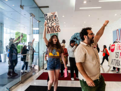 Protestors march into the lobby of 9200 Sunset with signs reading Palantir Tracks ICE Attacks on June 13, 2025, in Los Angeles, California.
