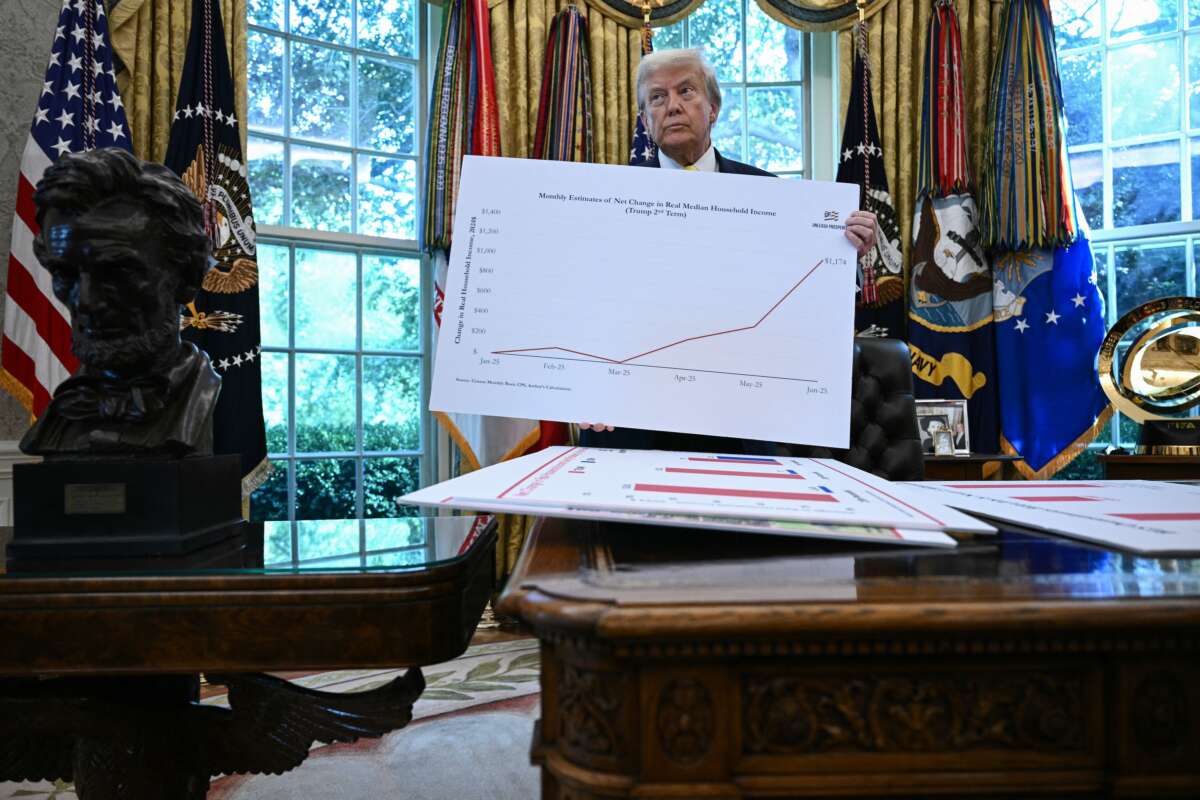 Donald Trump holds up a chart as he speaks about the economy in the Oval Office of the White House on August 7, 2025, in Washington, D.C.