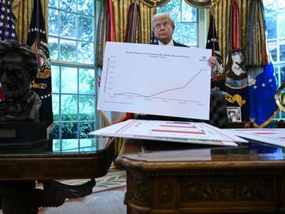 Donald Trump holds up a chart as he speaks about the economy in the Oval Office of the White House on August 7, 2025, in Washington, D.C.