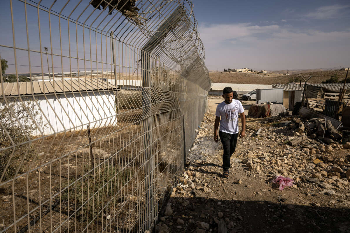 A Palestinian man walks along the fence that separates the village of Umm al-Khair from an Israeli settlement in the occupied West Bank, on November 2, 2025.