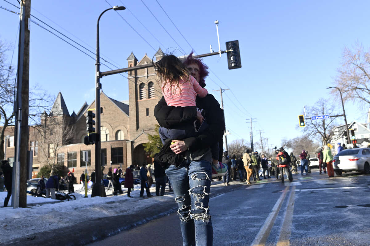 A person carries a child away from the scene where ICE agents were confronted by protestors after they arrested people from a residence on January 13, 2026, in Minneapolis, Minnesota.