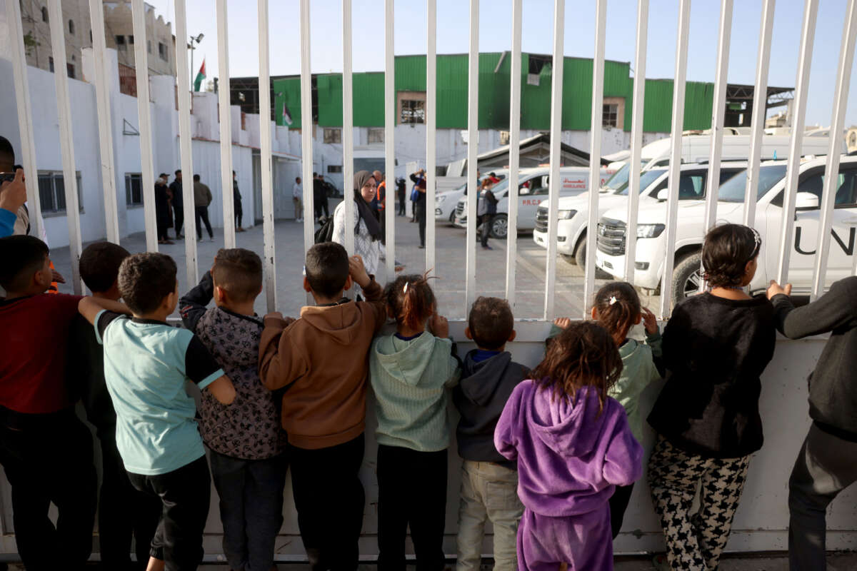Palestinian children watch as war-wounded Palestinians and other patients prepare to leave the Gaza Strip for treatment through the Rafah border crossing between the Gaza Strip and Egypt, in Khan Yunis in the southern Gaza Strip, on February 8, 2026.