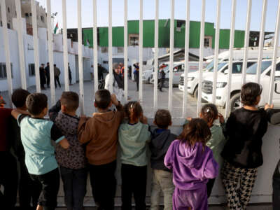 Palestinian children watch as war-wounded Palestinians and other patients prepare to leave the Gaza Strip for treatment through the Rafah border crossing between the Gaza Strip and Egypt, in Khan Yunis in the southern Gaza Strip, on February 8, 2026.