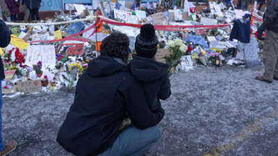 Two people look at a street memorial marking the spot where Alex Pretti was killed by ICE agents in Minneapolis