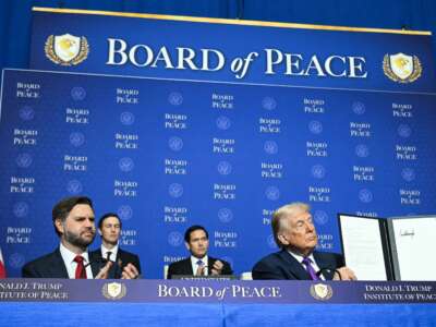 Vice President JD Vance, Donald Trump's son-in-law Jared Kushner, and Secretary of State Marco Rubio look on as Trump holds up a resolution during the inaugural meeting of the "Board of Peace" in Washington, D.C., on February 19, 2026. Trump used the meeting to threaten a U.S. escalation against Iran.
