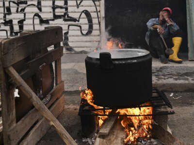 A man rests in front of a pot over a wood fire on a street in Havana, Cuba, on February 23, 2026.