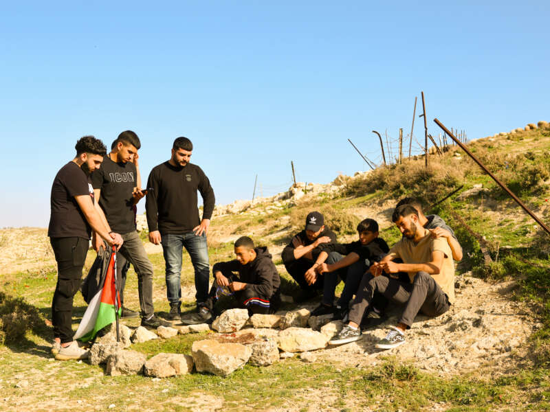 Friends of Nasrallah Abu Siyam, who was killed by Israeli settlers on February 19, 2026, gather at a makeshift memorial on a hill overlooking Mukhmas.
