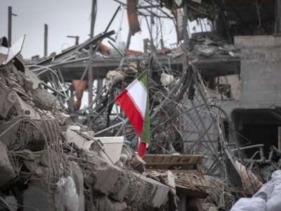 A national flag is placed on the ruins of a building that is destroyed during the U.S.-Israeli military campaign that strikes a residential area on March 9, 2026, in Tehran, Iran, on March 12, 2026.
