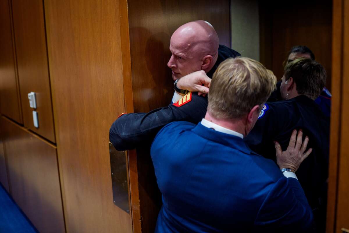 Brian McGinnis, a protester dressed in a military uniform, gets stuck in a door, injuring his arm as Sen. Tim Sheehy (R-MT) (R) and U.S. Capitol Police officers attempt to remove him from a Senate Armed Services Subcommittee hearing on Capitol Hill on March 4, 2026 in Washington, D.C.