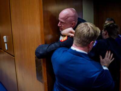 Brian McGinnis, a protester dressed in a military uniform, gets stuck in a door, injuring his arm as Sen. Tim Sheehy (R-MT) (R) and U.S. Capitol Police officers attempt to remove him from a Senate Armed Services Subcommittee hearing on Capitol Hill on March 4, 2026 in Washington, D.C.