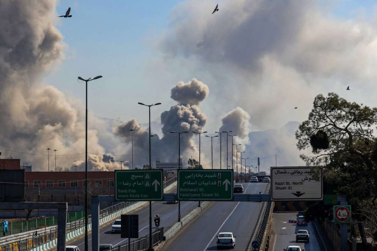Motorists drive along an expressway as plumes of smoke rise after strikes on Tehran on March 5, 2026.