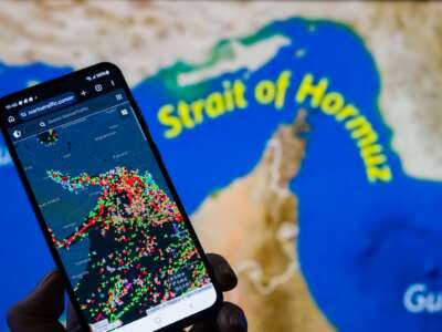 A MarineTraffic map showing ship movements in the Strait of Hormuz is displayed on a smartphone screen with a map in the background in this photo illustration, as commercial vessel traffic through the key oil shipping lane decreases amid the ongoing conflict involving Iran.