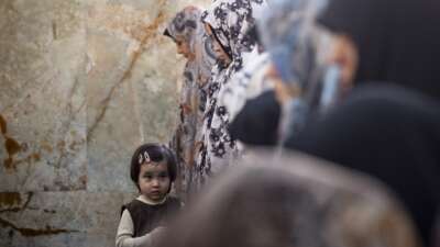 A young girl looks on as veiled worshippers pray during an Eid al-Fitr mass prayer ceremony in the Shahr-e Rey neighborhood in southern Tehran, Iran, on March 21, 2026, amid the United States and Israel's bombardments in Iran.