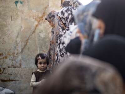 A young girl looks on as veiled worshippers pray during an Eid al-Fitr mass prayer ceremony in the Shahr-e Rey neighborhood in southern Tehran, Iran, on March 21, 2026, amid the United States and Israel's bombardments in Iran.