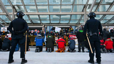 Police look on as people attend a demonstration at the Minneapolis-Saint Paul International Airport amid a surge of federal immigration authorities in the area in St. Paul, Minnesota.