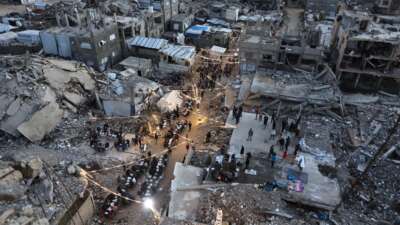 Displaced Palestinians gather for their fast-breaking iftar meal amid the rubble of destroyed buildings at the Jabalia refugee camp in the northern Gaza Strip, during the Muslim holy fasting month of Ramadan, on February 23, 2026.